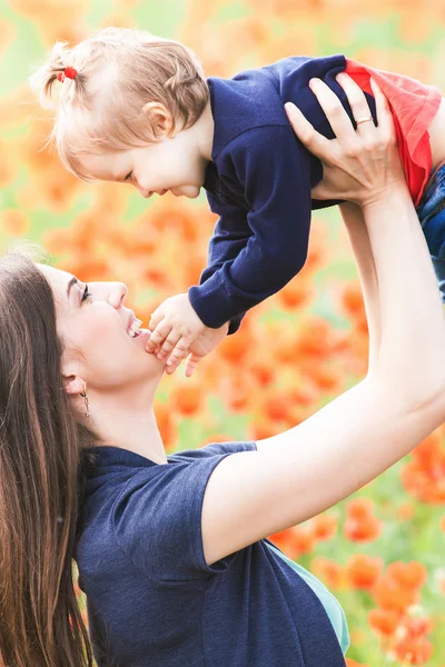 Madre con divertente bambino all'aperto al campo di fiori di papavero — Foto Stock