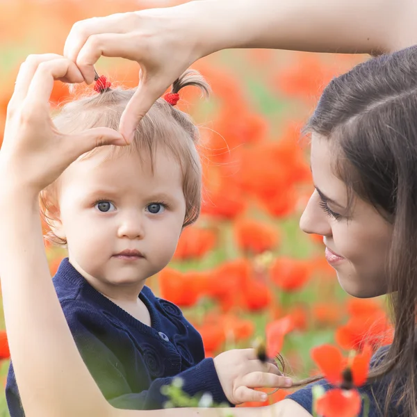 Mère avec drôle d'enfant en plein air au champ de fleurs de pavot — Photo