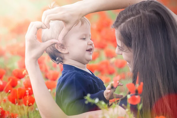 Madre con niño divertido al aire libre en el campo de flores de amapola —  Fotos de Stock