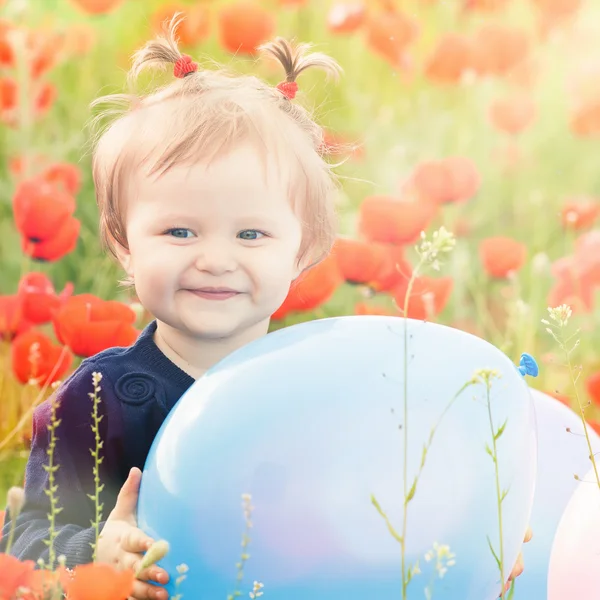 Funny child holding a balloon outdoor at poppy field — Stock Photo, Image