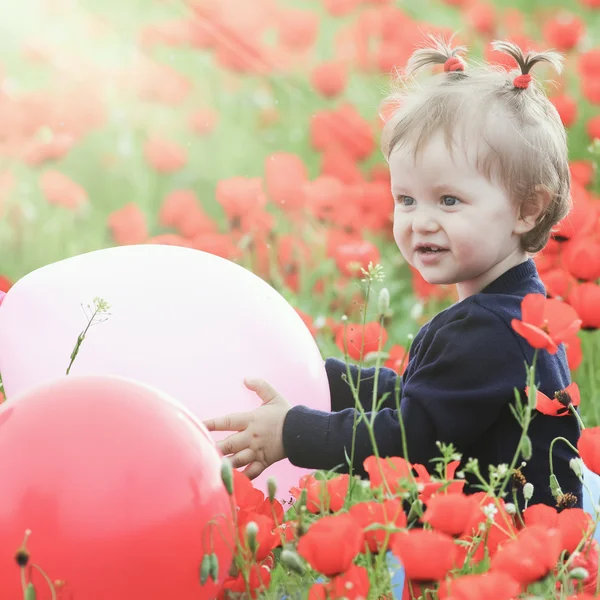 Funny child holding a balloon outdoor at poppy field — Stock Photo, Image
