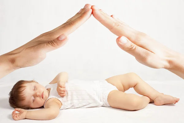 Geste mains de la maison au-dessus bébé endormi — Photo