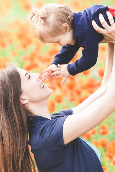 Madre con niño divertido al aire libre en el campo de flores de amapola —  Fotos de Stock