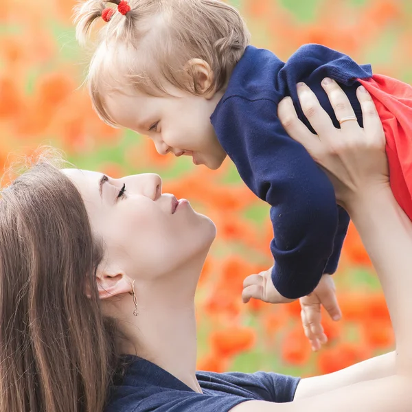 Mère avec drôle d'enfant en plein air au champ de fleurs de pavot — Photo