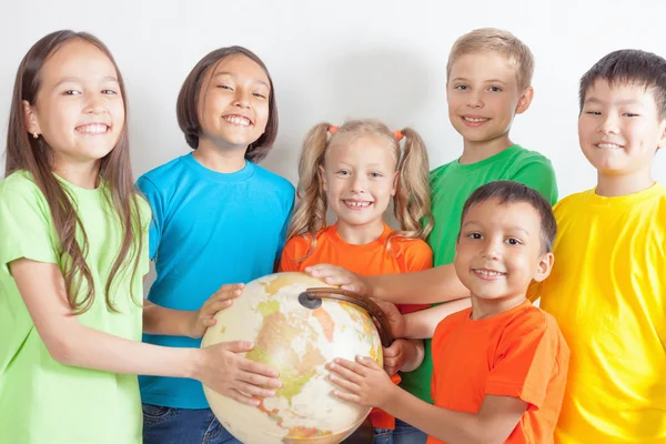 Grupo de niños internacionales sosteniendo globo terráqueo — Foto de Stock