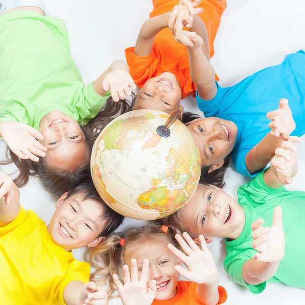 Grupo de niños divertidos internacionales con globo terráqueo — Foto de Stock