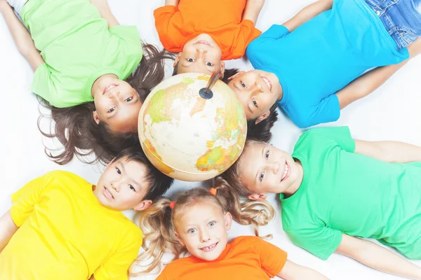 Grupo de niños internacionales sosteniendo globo terráqueo — Foto de Stock