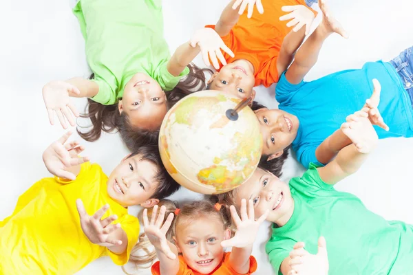 Grupo de niños internacionales sosteniendo globo terráqueo — Foto de Stock