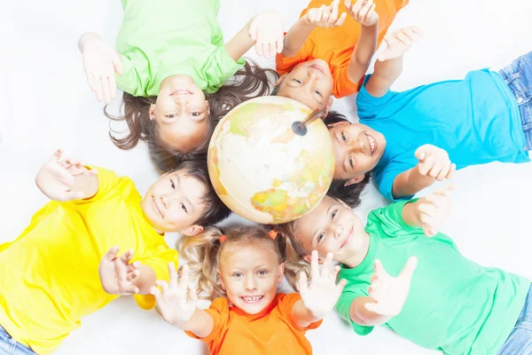 Grupo de niños divertidos internacionales con globo terráqueo — Foto de Stock