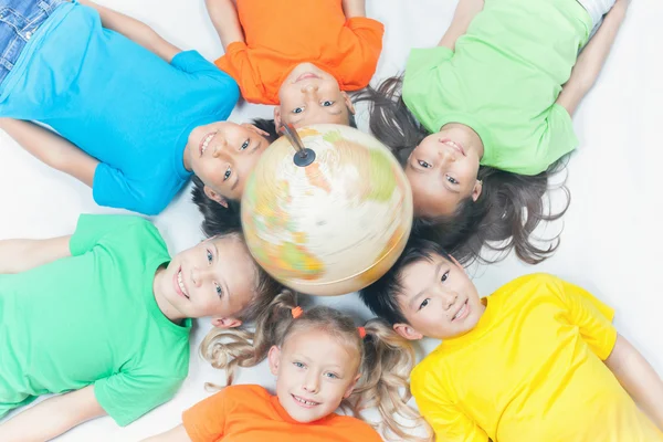 Grupo de niños internacionales sosteniendo globo terráqueo — Foto de Stock