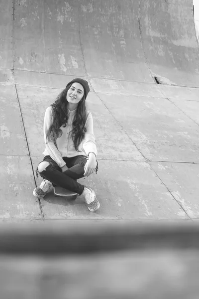 Impressionante ragazza skateboarder con skateboard seduta all'aperto allo skatepark — Foto Stock