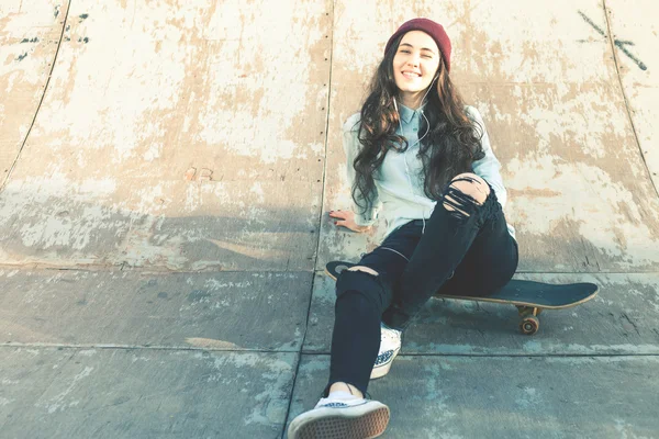 Hipster-Skateboarder-Mädchen mit Skateboard sitzt im Skatepark — Stockfoto