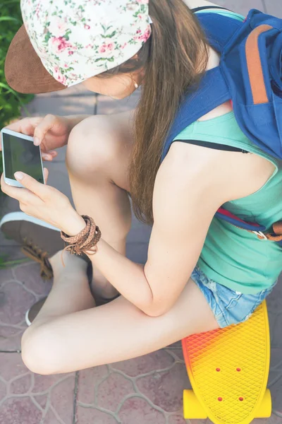 Close-up of skateboarder girl sitting on skateboard outdoor — Stock Photo, Image