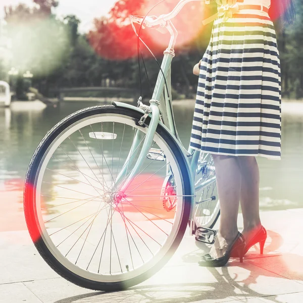 Młoda dziewczyna stoi w pobliżu ogrodzenia w pobliżu zabytkowych rowerów w parku — Zdjęcie stockowe