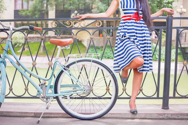 Junges Mädchen steht in der Nähe von Zaun neben Oldtimer-Fahrrad im Park — Stockfoto