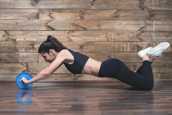 Mujer atractiva con el estómago delgado hacer ejercicios abdominales con rueda —  Fotos de Stock