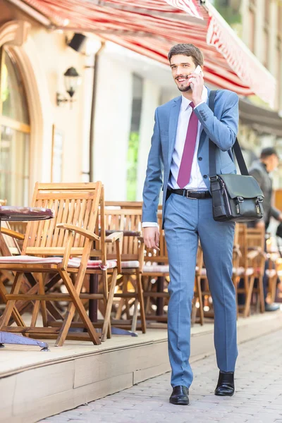Successful businessman talking by mobile phone and walking — Stock Photo, Image