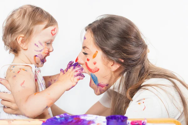 Gelukkig moeder en baby spelen met geschilderde gezicht door verf — Stockfoto