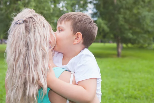 Madre con su hijo caminando al aire libre. Niño besar mamá —  Fotos de Stock