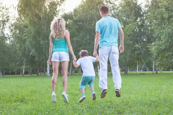 Ευτυχισμένο παιδί με τους γονείς μαμά και ο πατέρας πηδά πάνω. Οικογένεια. — Φωτογραφία Αρχείου