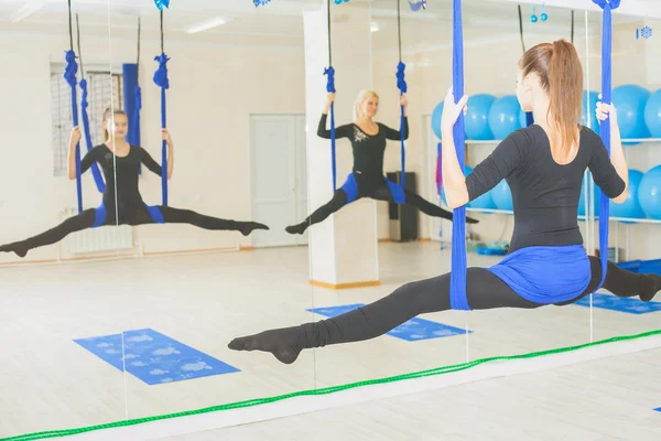 Mujeres jóvenes haciendo ejercicio de yoga aéreo o yoga antigravedad —  Fotos de Stock