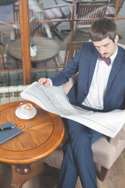 Kafede bir gazete okuyor, yas işadamı