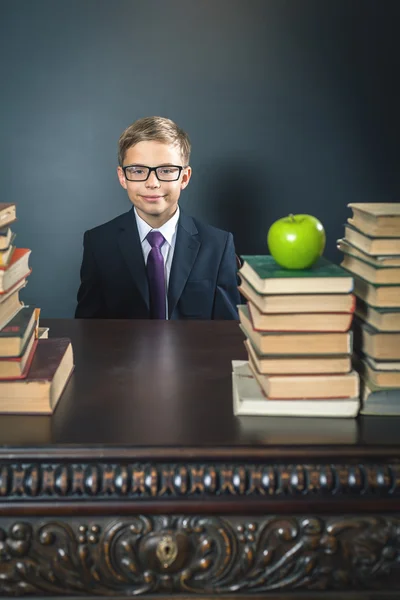 Smart school chłopiec siedzi przy stole z wielu książek — Zdjęcie stockowe