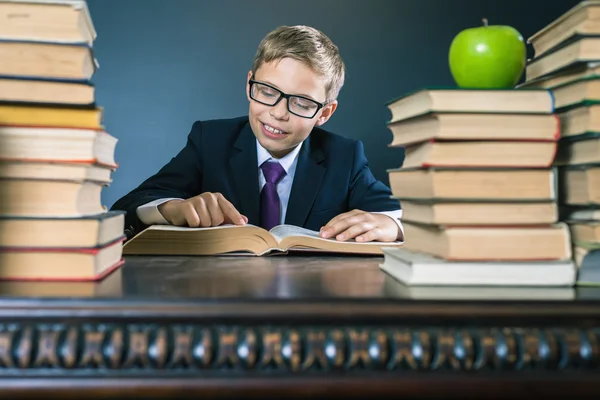 Smart school boy reading a book at library — Stock Photo, Image