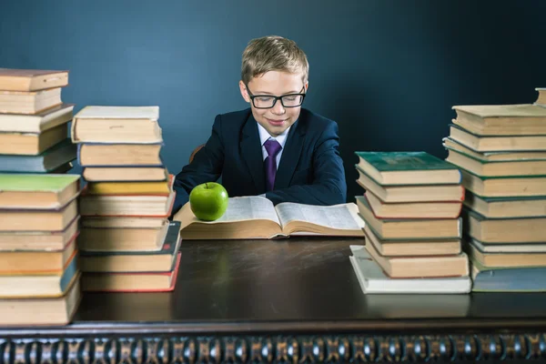 Smart school boy reading a book at library — Stock Photo, Image