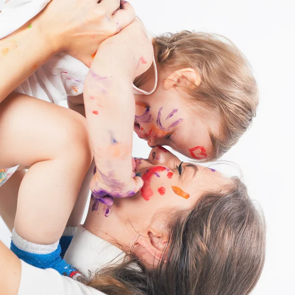 Glad mamma och baby spelar med målat ansikte av paint — Stockfoto