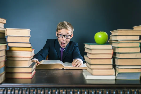 Chłopiec szkoły śmieszne, czytając książkę w bibliotece. Żart! — Zdjęcie stockowe