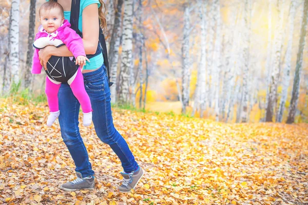 Щаслива мати, що носить дитину за допомогою ергономічного дитячого перевізника — стокове фото
