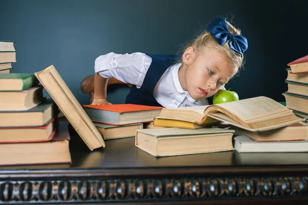 Smart skola flicka läsa en bok på biblioteket — Stockfoto