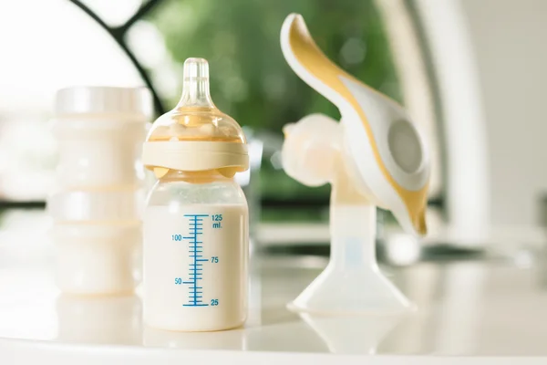Garrafa de bebê com leite e bomba de mama manual — Fotografia de Stock