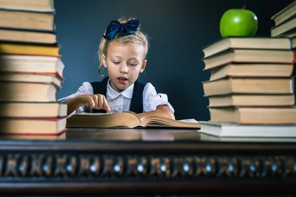 Smart skola flicka läsa en bok på biblioteket — Stockfoto