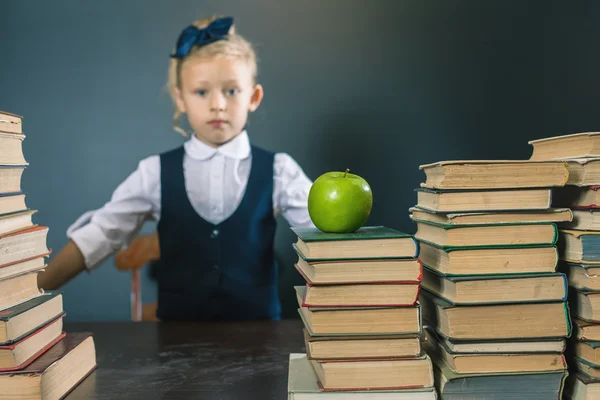 Söt skolflicka sitter vid bordet med många böcker — Stockfoto