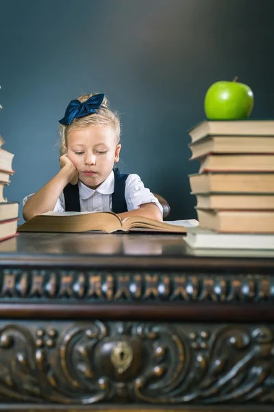 Smart skola flicka läsa en bok på biblioteket — Stockfoto