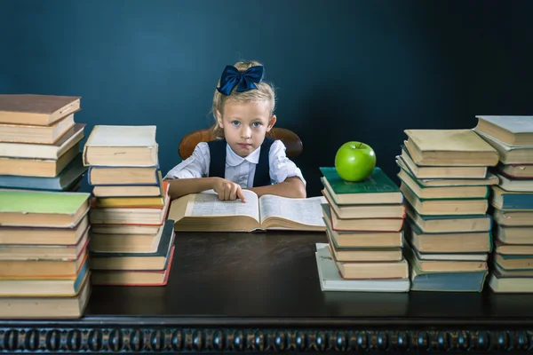 Smart skola flicka läsa en bok på biblioteket — Stockfoto
