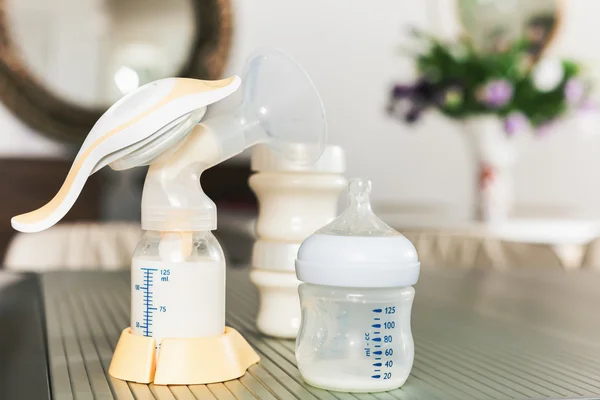 Baby bottle with milk and manual breast pump — Stock Photo, Image