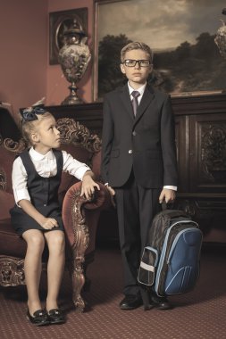 Okul üniforması giymiş, takım elbiseli okul çocukları. Okul çantası