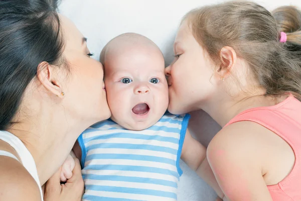 Happy family mother with daughter kissing baby — Stock Photo, Image