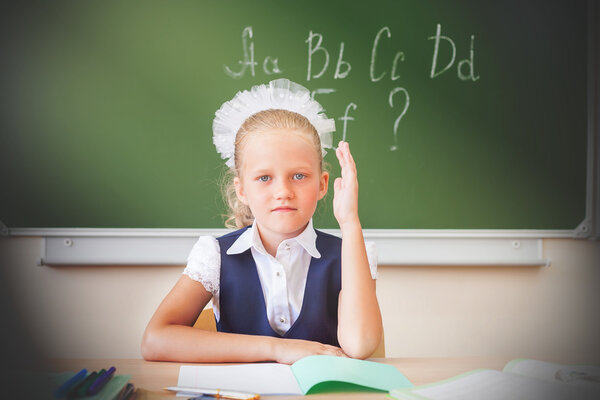 Schoolgirl sitting at desk, school classroom, english alphabet