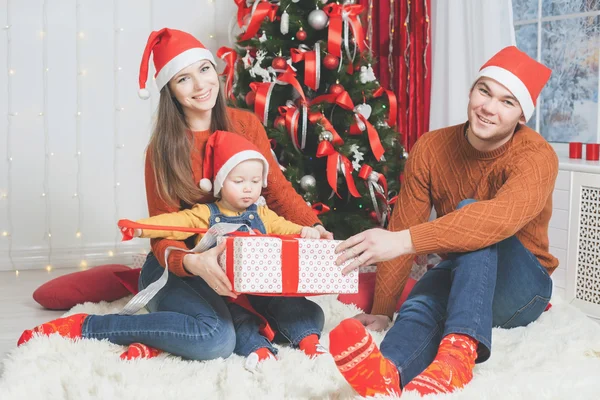 Far, mor och spädbarn holding Cristmas gåva nära julgran — Stockfoto