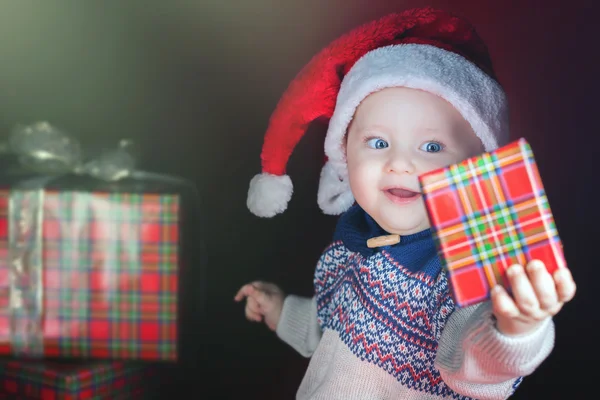 Χριστούγεννα μωρό φορώντας ένα καπέλο Santa Claus κρατώντας ένα δώρο — Φωτογραφία Αρχείου