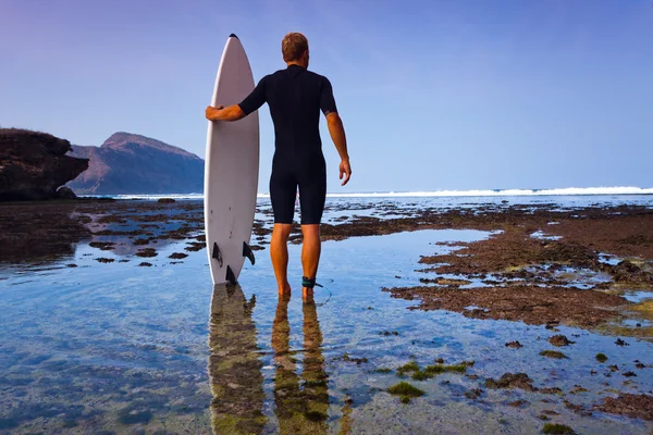 Surfer met surfboard op een kustlijn — Stockfoto