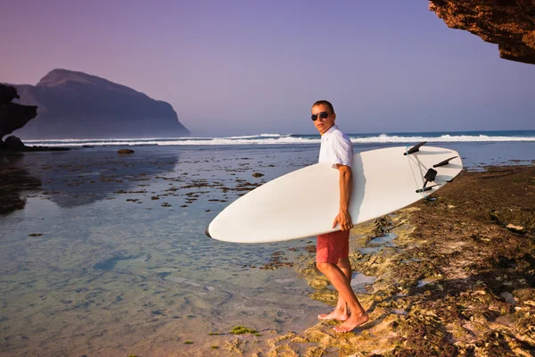 Adam sörfçü bir sahil şeridi üzerinde surfboard ile. Bali. Endonezya — Stok fotoğraf