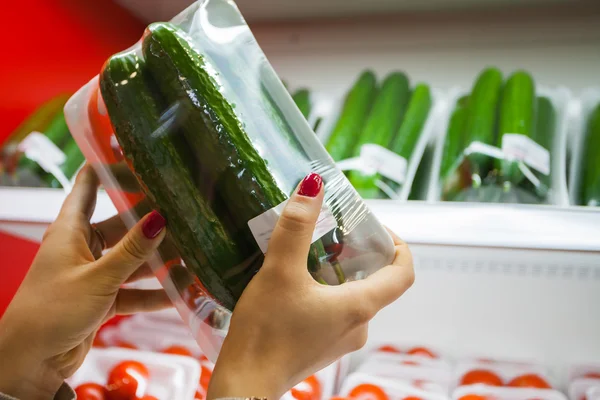 Pepino embalado com mão de mulher no supermercado — Fotografia de Stock