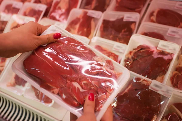 Packaged meat with woman hand in the supermarket — Stock Photo, Image