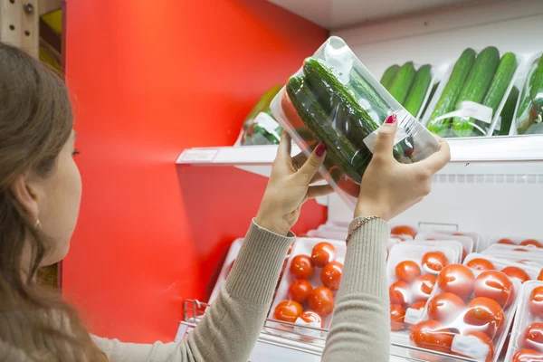 Pepino embalado com mão de mulher no supermercado — Fotografia de Stock