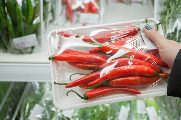 Balí chilli papričky s ženskou ruku v supermarketu — Stock fotografie